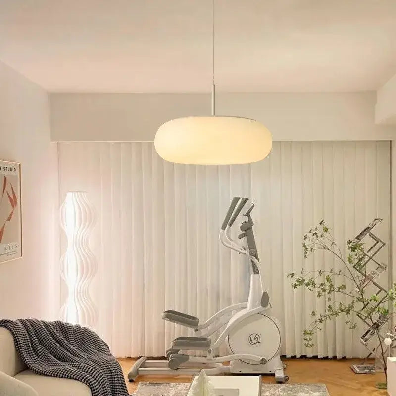 A modern softly glowing decorbites cream apple pendant light with a rounded design hanging in a bedroom setting