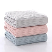 Stack of three folded decorbites cotton waffle towels in soft gray blush pink and muted blue for bathroom use