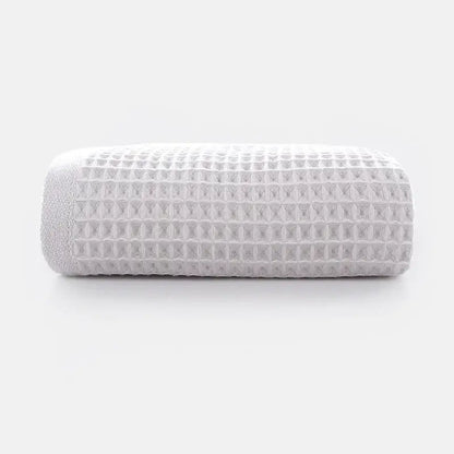 A neatly rolled white cotton waffle towel with soft texture from decorbites cotton waffle towel bath set in gray blush and blue