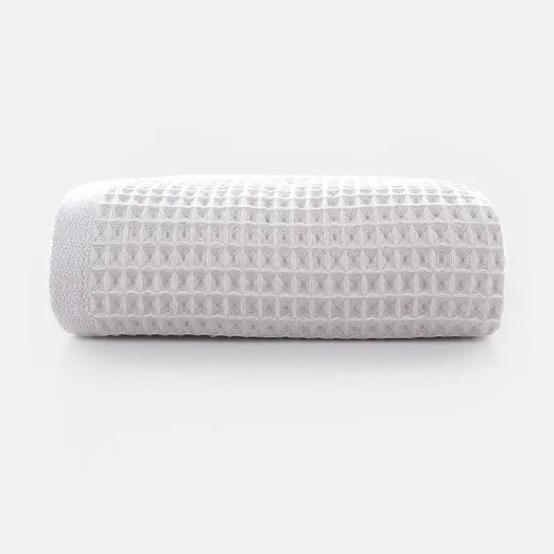 A neatly rolled white cotton waffle towel with soft texture from decorbites cotton waffle towel bath set in gray blush and blue