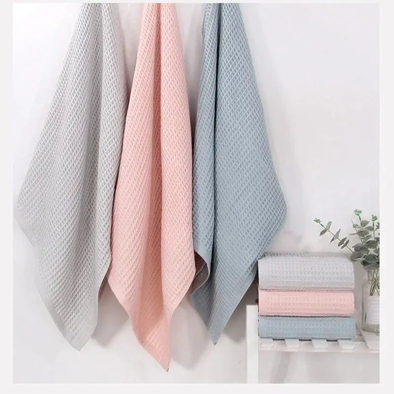 Three cotton waffle towels in soft gray blush and blue hang neatly as a waffle towel bath set for decorbites bathroom