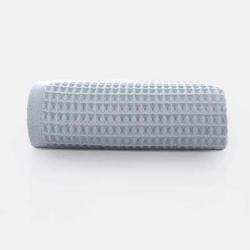 A neatly rolled soft gray cotton waffle towel with a textured grid pattern from the decorbites waffle towel bath set