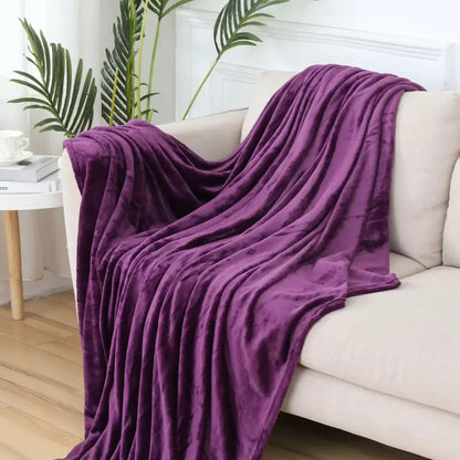 A plush deep purple velvet throw blanket draped over a beige sofa highlighting decorbites cozy flannel warmth