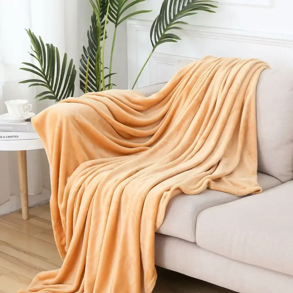 A plush peach fleece throw blanket draped over a beige sofa showcasing decorbites cozy flannel warm design