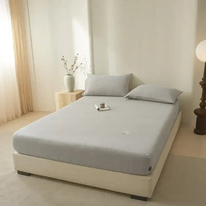 Soft light gray cotton fitted sheet with soft texture subtle stitching and small embroidered logo decorbites cotton fitted sheet