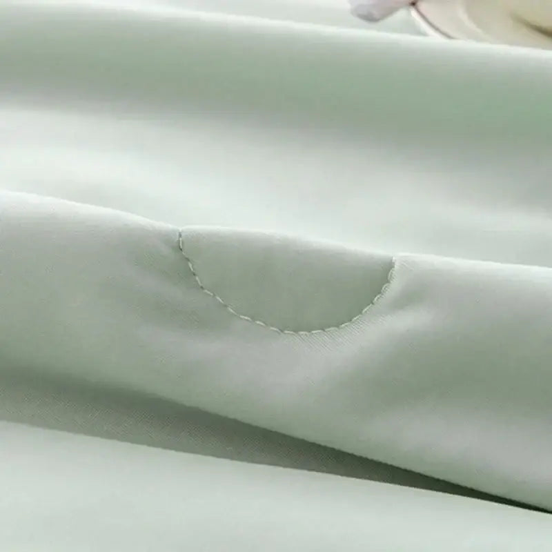 Soft mint green decorbites cooling quilt with subtle sheen and delicate curved stitching for bedroom comfort