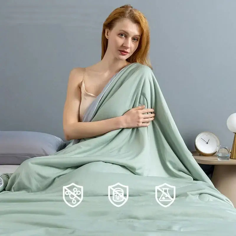 A soft mint green satin-like decorbites cooling quilt draped over a woman’s shoulders for bedroom comfort
