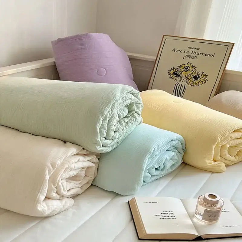 Pastel-colored soft peach cotton muslin cooling wrinkled yarn quilts in mint green pale yellow and light blue rolled on bed