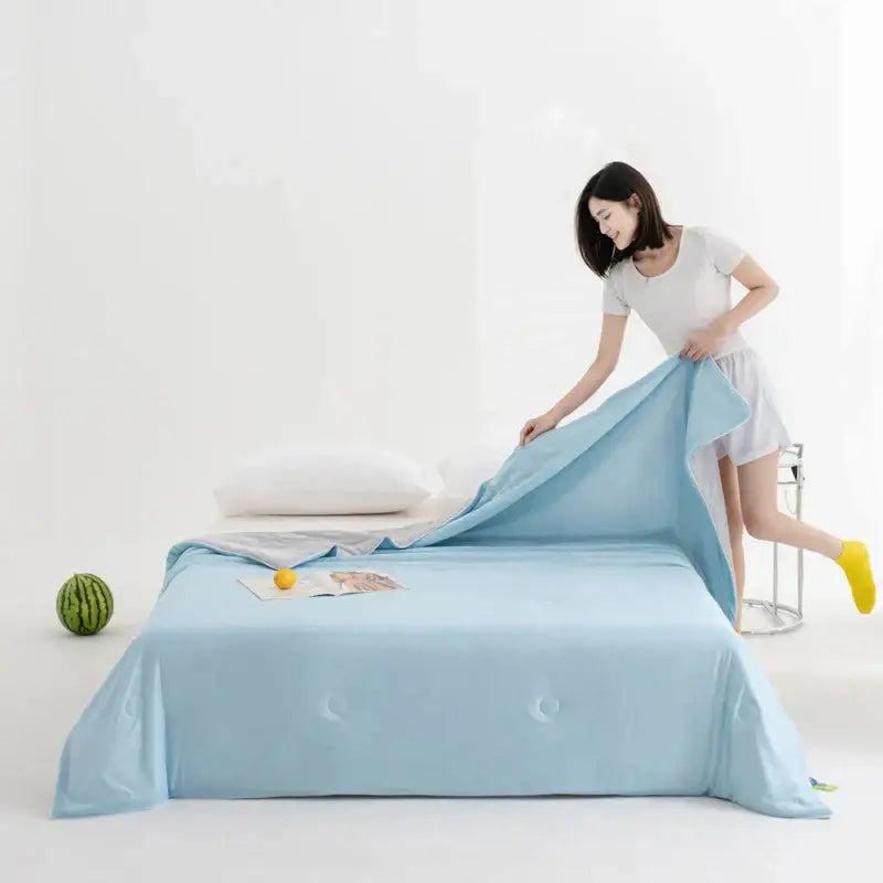Soft teal and gold cool fibre summer quilt with light blue satin bed sheet and subtle tufted detailing by decorbites