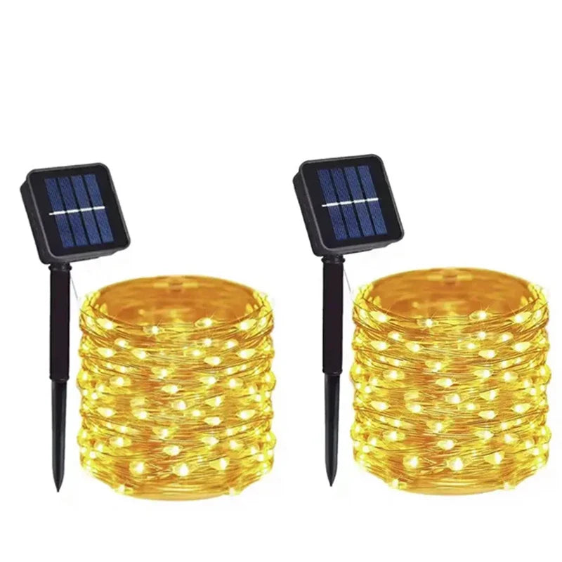 Golden solar fairy light string with black stake-mounted solar panels for outdoor garden and tree decoration