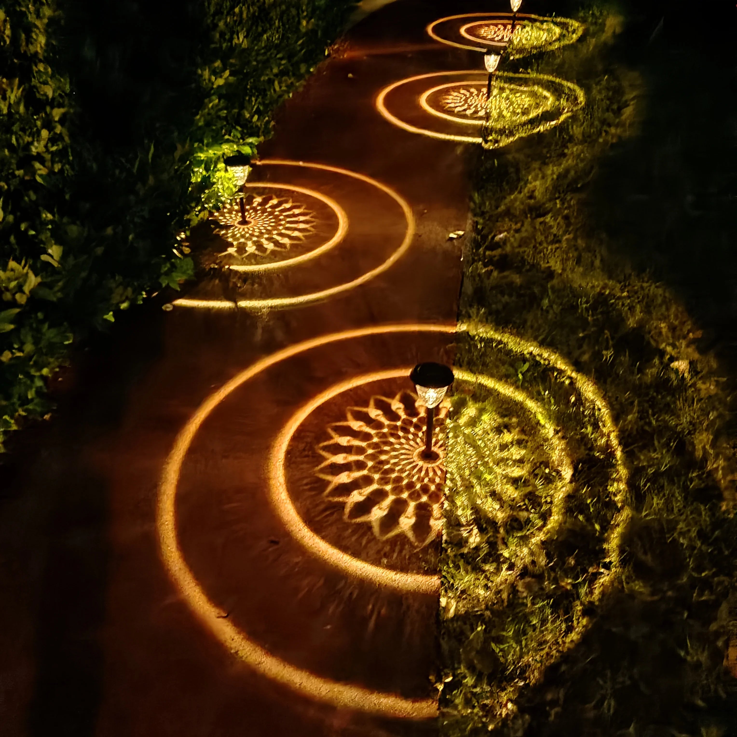 Solar light outdoor waterproof pathway lights projecting warm-toned circular floral patterns on garden lawn