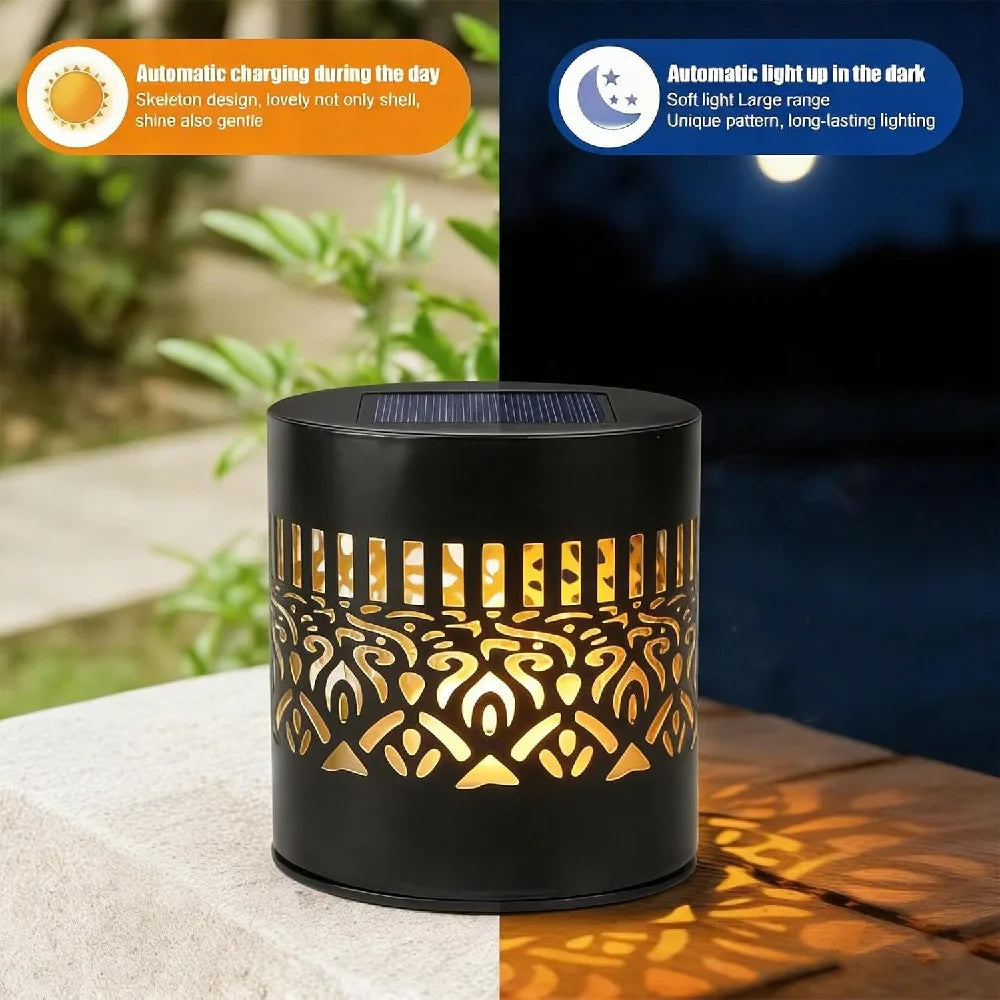Black cylindrical solar mandala projection light with intricate cutout patterns casting warm decorative shadows outdoors