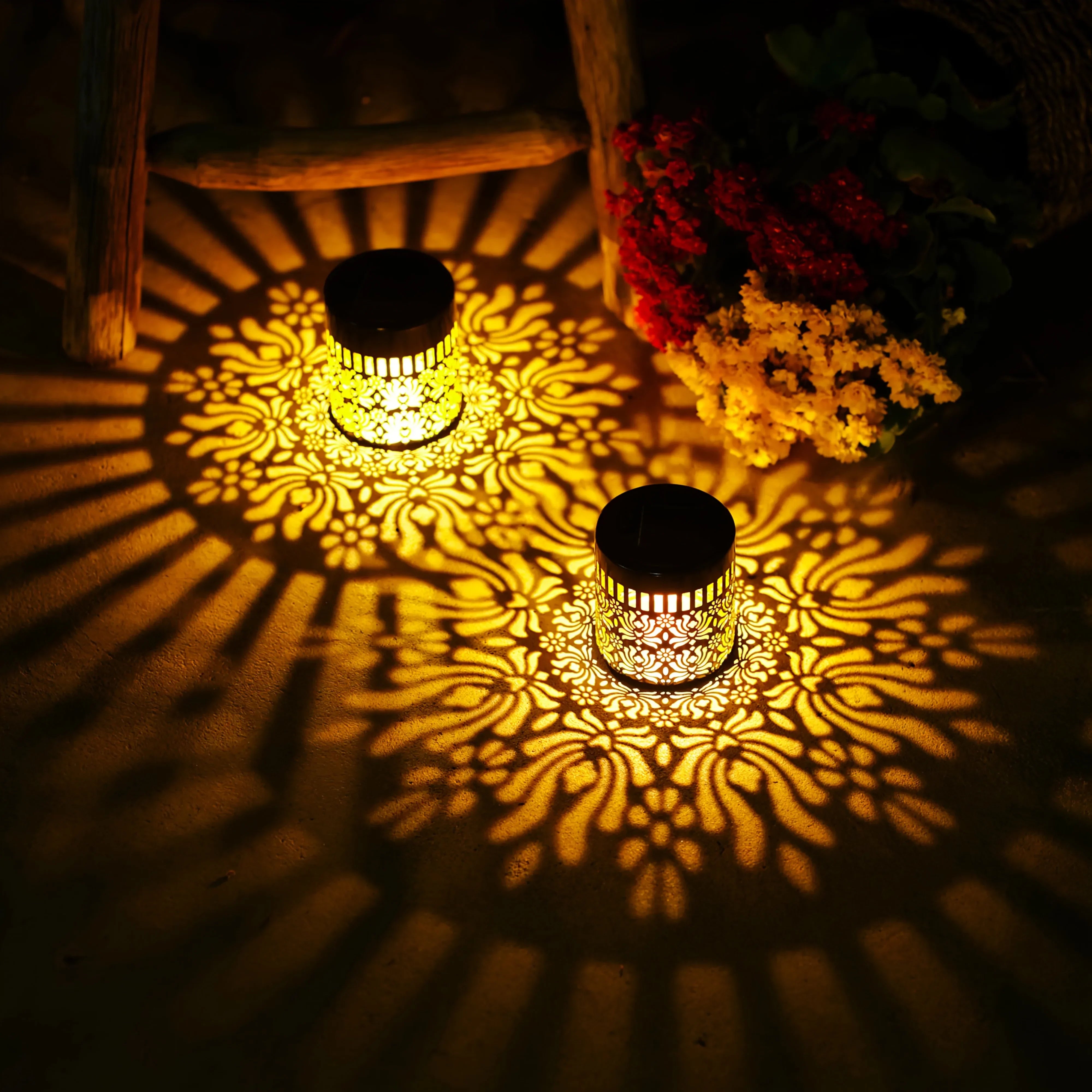 Two golden solar-powered datura lanterns with intricate floral cutouts casting warm patterns for garden decor