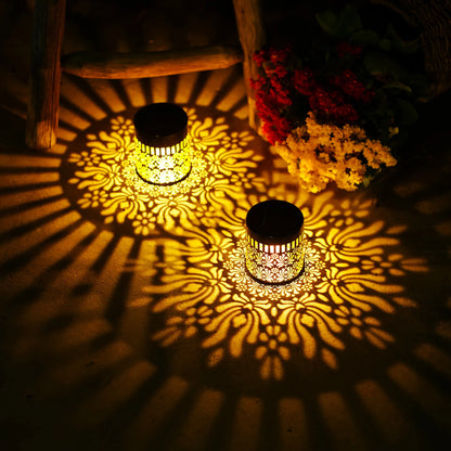 Two golden solar-powered datura lanterns with intricate floral cutouts casting warm patterns for garden decor