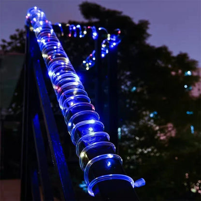 A glowing blue solar led rope light with clear spiral bulbs wrapped around a dark outdoor railing for garden use