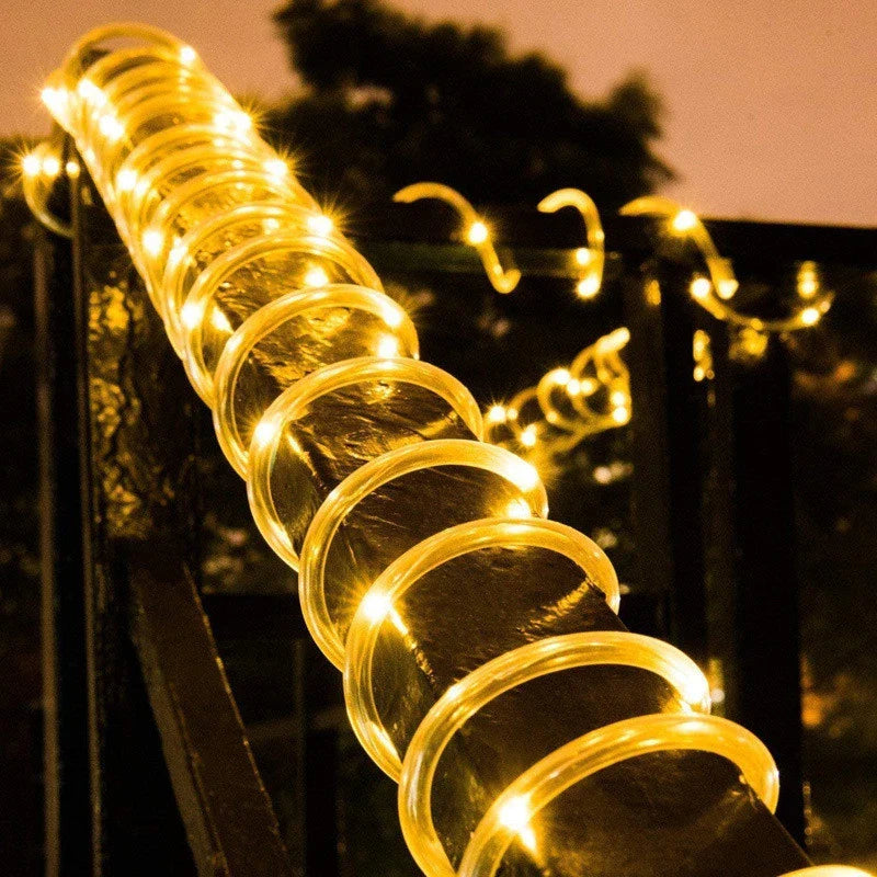 Solar rope lights with warm golden spiral led bulbs wrapped around a dark metal railing for outdoor garden use