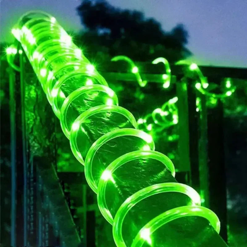 A glowing green solar rope light with embedded led bulbs for outdoor garden and deck lighting with waterproof design