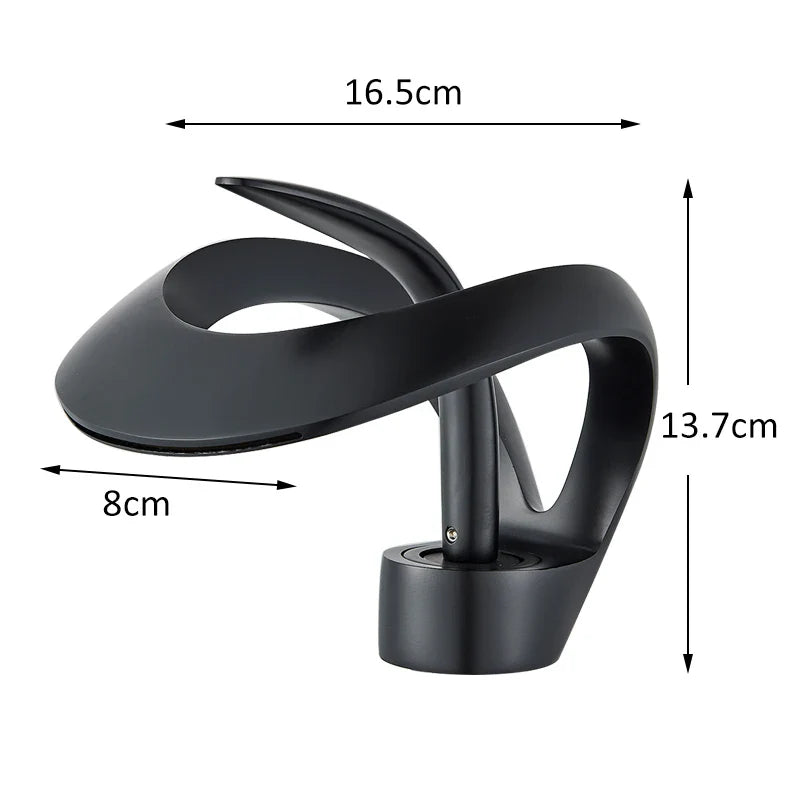 Black matte-finished abstract sculpture with flowing curves and solid base displayed beside single hole waterfall basin faucet for cold water use