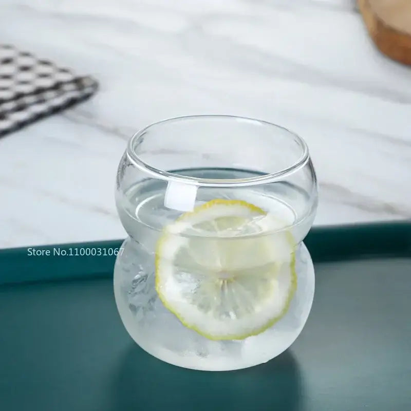 Clear glass cold brew coffee tumbler with rounded bulbous shape and lemon slice floating in water for brew coffee cup use