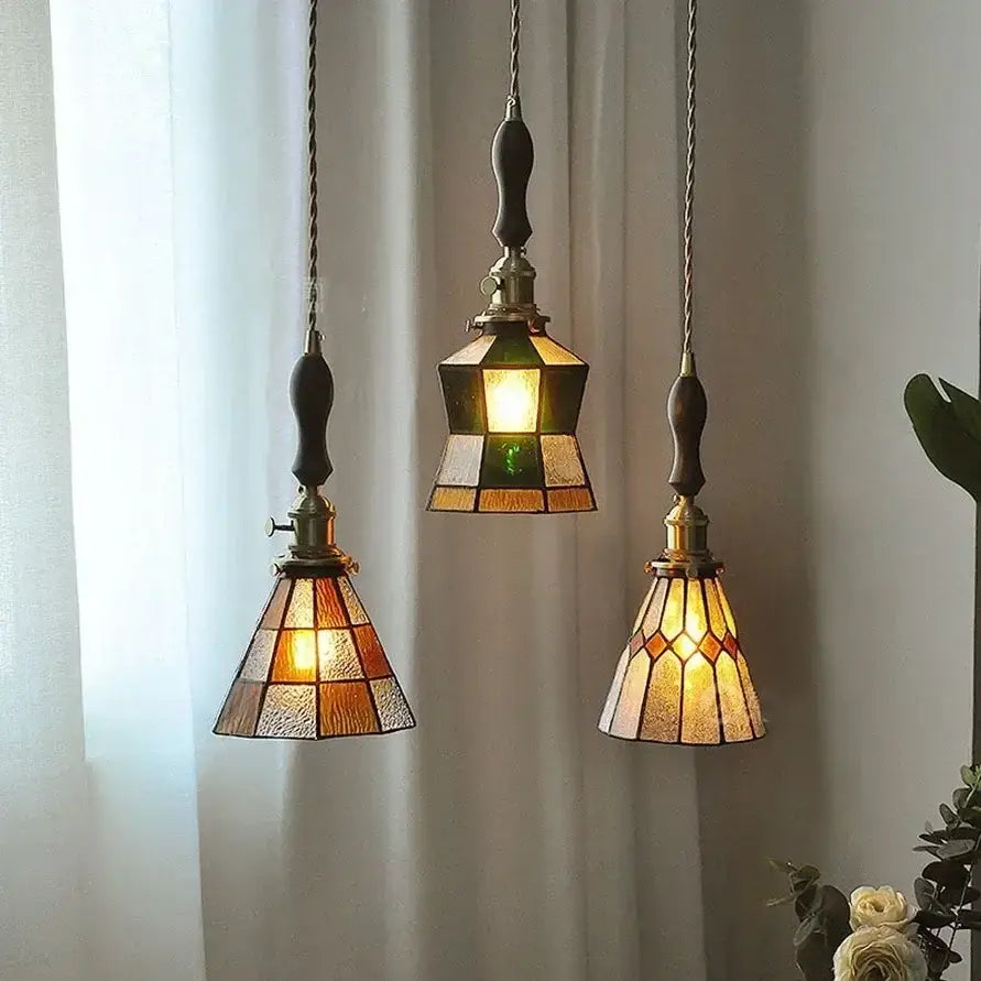 Three vintage-style stained glass pendant lights with warm amber and green hues featuring colorful glass copper finish