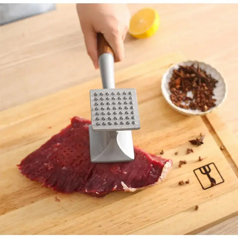 Silver stainless steel and wood double faced meat tenderizer with wooden handle and grid of small indentations on flat surface