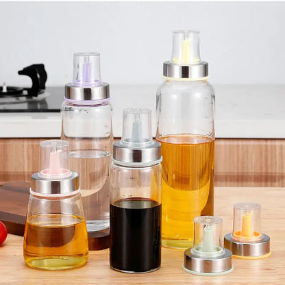 Clear glass spray bottles with stainless steel bottle cap stoppers and colorful silicone kitchen nozzles filled with oils