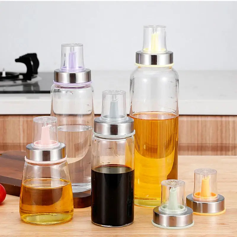 Clear glass spray bottles with stainless steel bottle cap stoppers and colorful silicone kitchen nozzles filled with oils