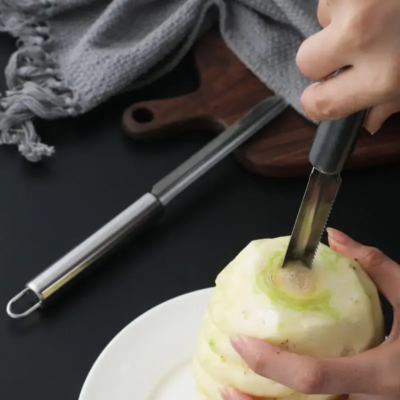 Black-handled stainless steel decorbites fruit corer with serrated blade peeling a white radish in kitchen use