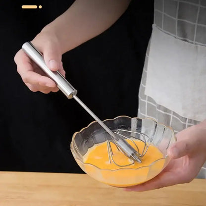 A sleek stainless steel hand pressure egg beater with polished handle and fine wire coils for kitchen whisk mixing