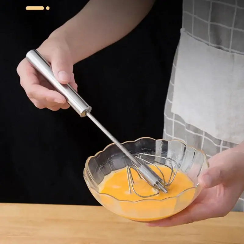 A sleek stainless steel hand pressure egg beater with polished handle and fine wire coils for kitchen whisk mixing