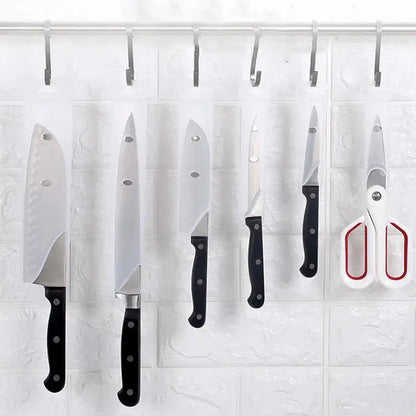 Set of five stainless steel kitchen knives and scissors with black handles hanging on hooks featuring decorbites knife scabbard