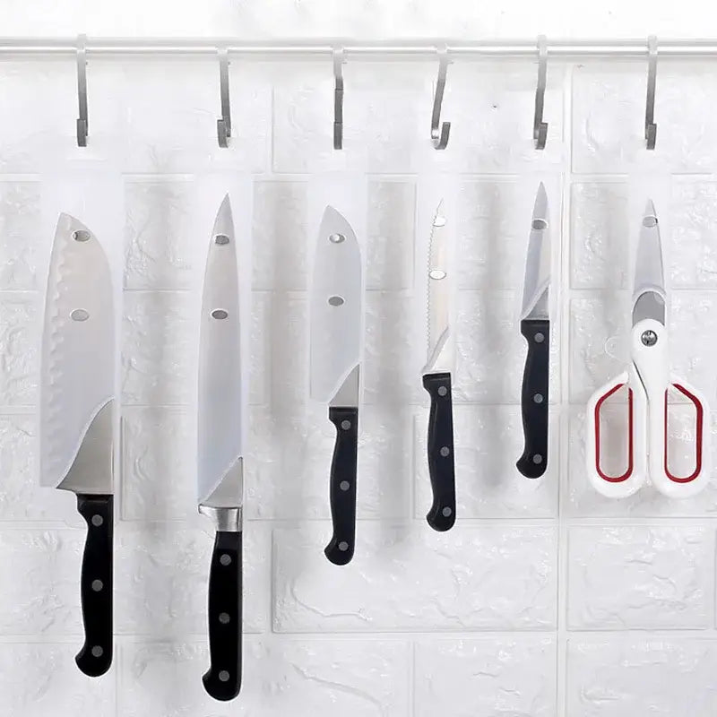 Set of five stainless steel kitchen knives and scissors with black handles hanging on hooks featuring decorbites knife scabbard