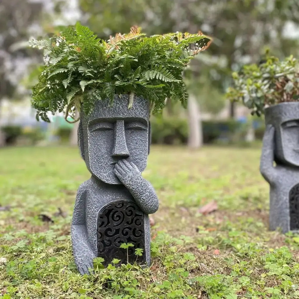 Gray stone easter island statue sculpture garden moai planter with intricate carvings and fern arrangement on top