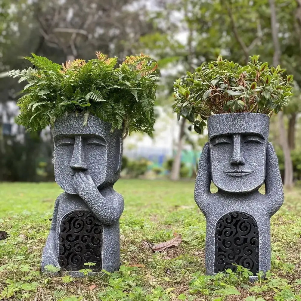 Stone gray easter island statue sculpture garden planter featuring gray stone moai heads with carved faces and green foliage