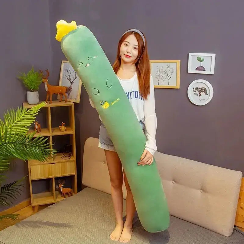 A plush green cucumber-shaped decorbites cylindrical soft pregnancy sleep pillow with yellow top and embroidered face