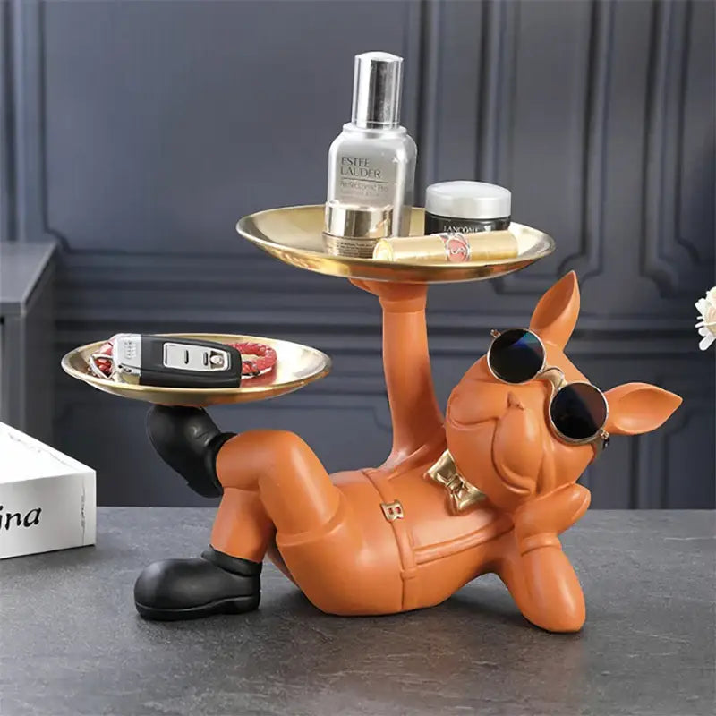 Orange pig figurine with sunglasses and bow tie holding two gold trays alongside stylish black and gold bulldog figurine sculpture decorbites