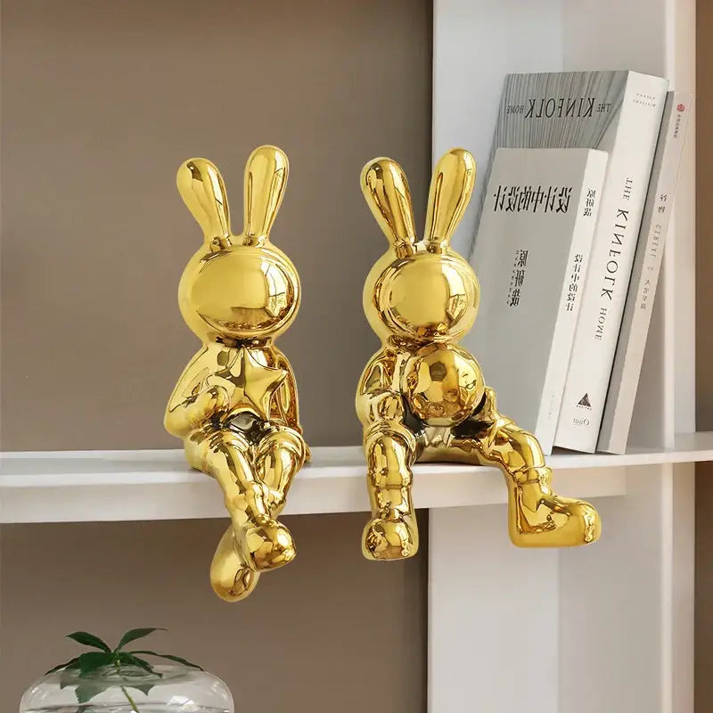 Stylized gold ceramic rabbit sculpture set featuring two glossy reflective rabbit sculptures for living room decor