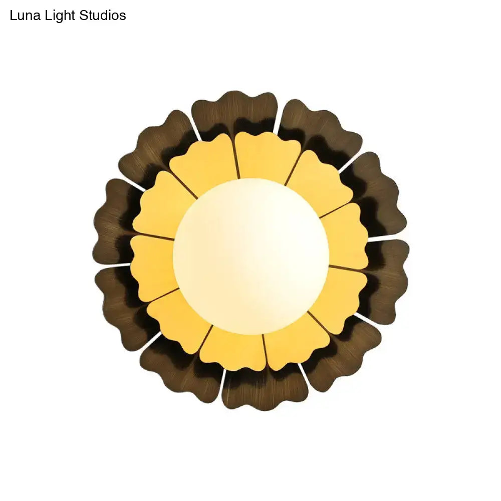Circular sunflower-inspired ceiling light with warm yellow center and dark brown petals featuring matte white glass ball