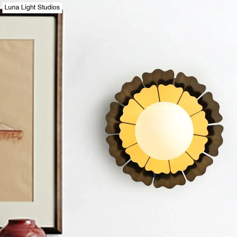 A modern sunflower yellow and wood wall sconce with warm layered petals and a matte white glass ball for bedroom use