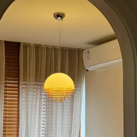 A warm yellow dome-shaped acrylic pendant light with a tiered metal frame for dining room use