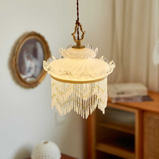 Cream-colored vintage-style chandelier with intricate beaded fringe and ornate metal frame.
