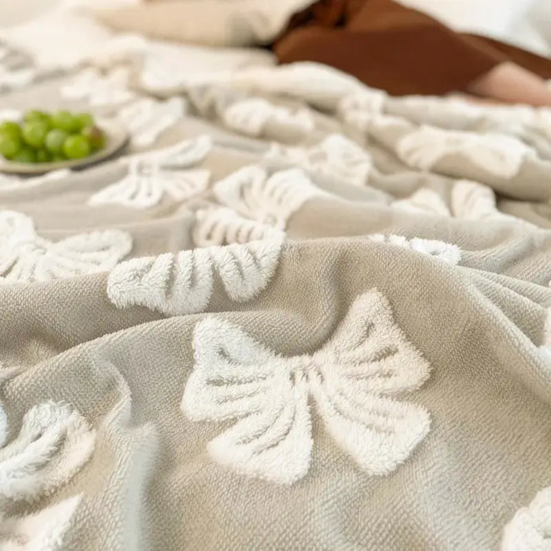 A soft taupe wool blanket with white plush bow appliqués featuring decorbites butterfly jacquard design