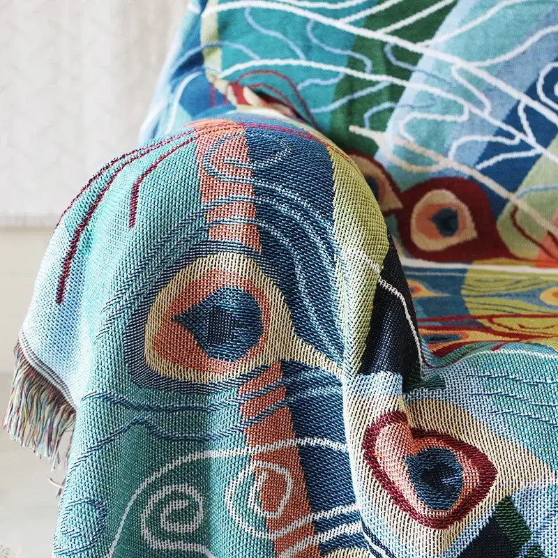 A decorbites knit sofa blanket with a vibrant peacock design in teal orange and red as a sofa blanket cover