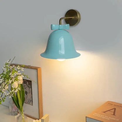 A light blue ceramic bowknot bell wall lamp with a brass mounting bracket from the decorbites bowknot bell collection