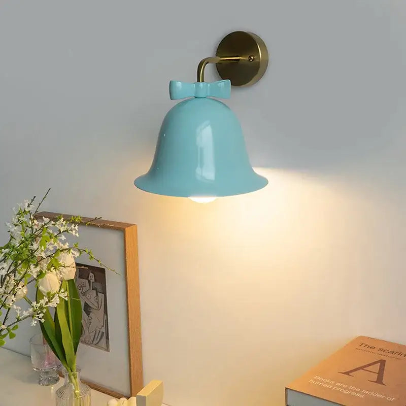 A light blue ceramic bowknot bell wall lamp with a brass mounting bracket from the decorbites bowknot bell collection