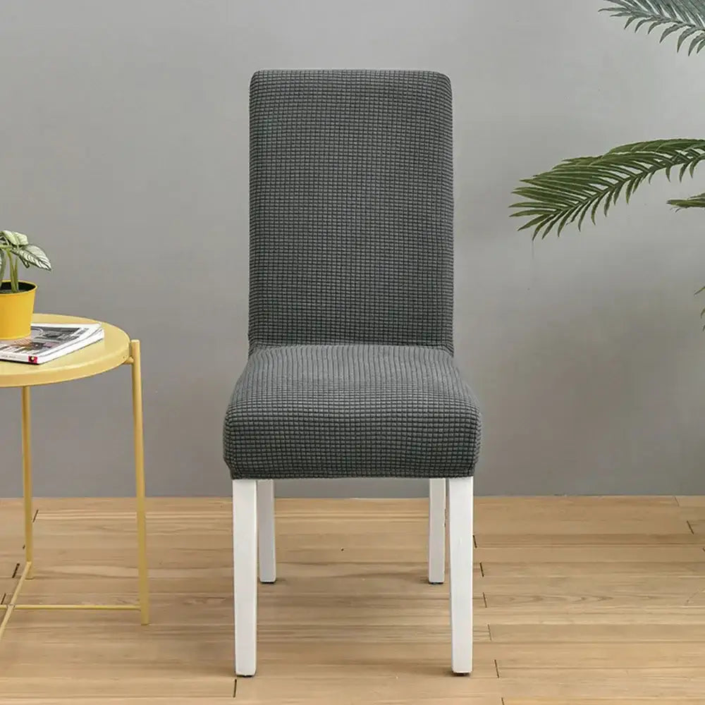 Gray textured chair cover with subtle checkered pattern snugly fitted over a modern dining chair decorbites blue quilted chair cover
