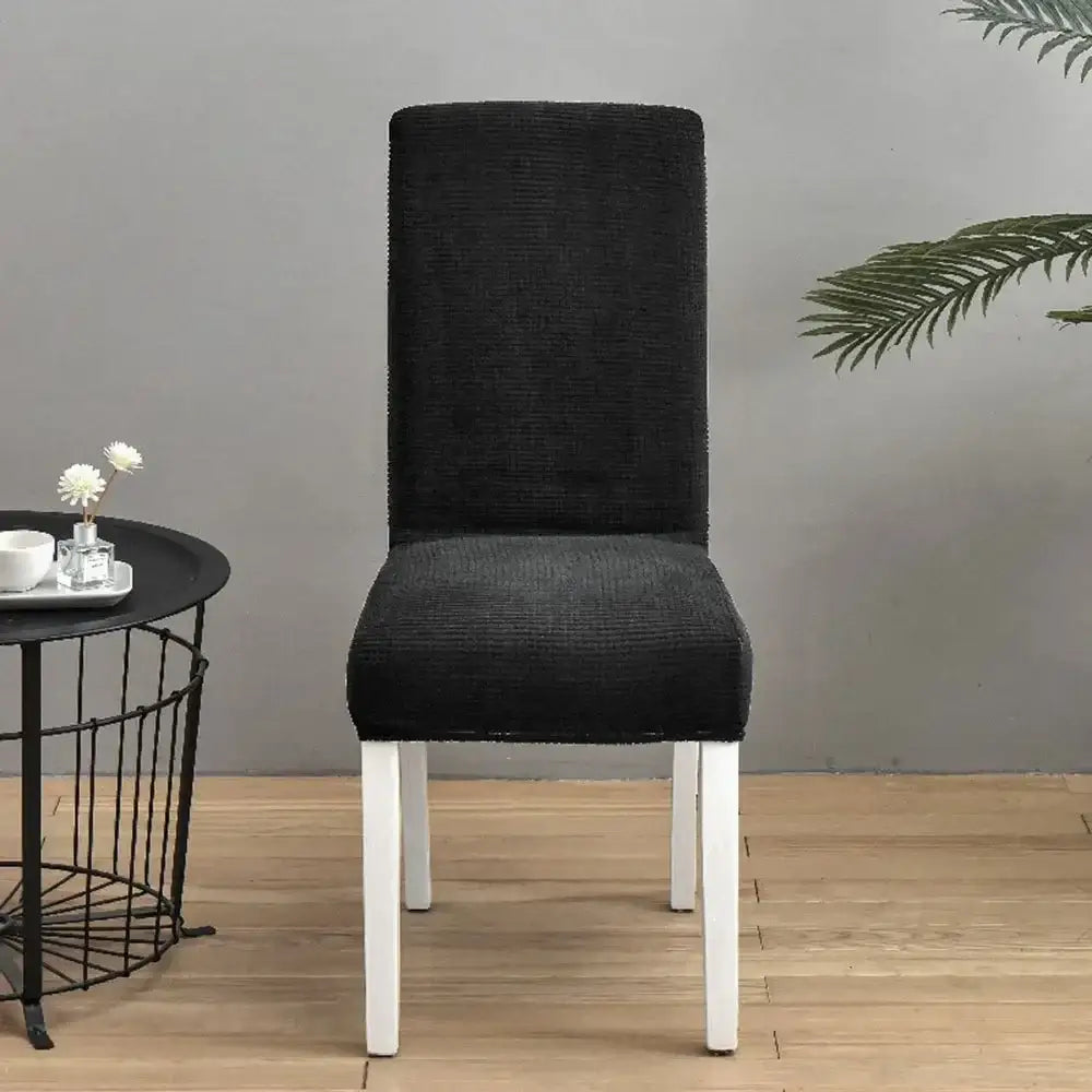 Black textured chair cover snugly fitted over high-back dining chair with white legs by decorbites blue quilted chair cover