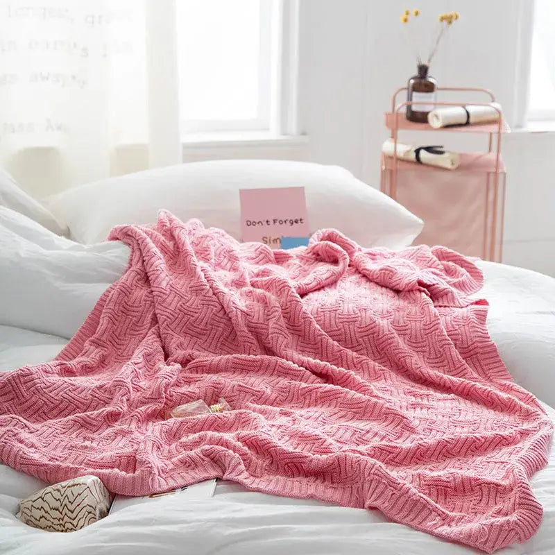 A soft pink knitted throw blanket with textured herringbone pattern matching decorbites cozy jacquard style