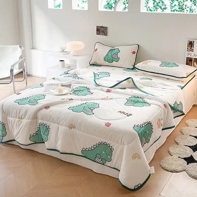 White quilted blanket set with green cartoon dinosaurs and strawberries accented with teal piping for decorbites cool summer use