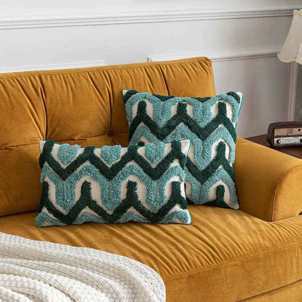 Two textured teal and dark green boho tufted pillow covers with zigzag pattern on cream background on orange velvet sofa decorbites boho